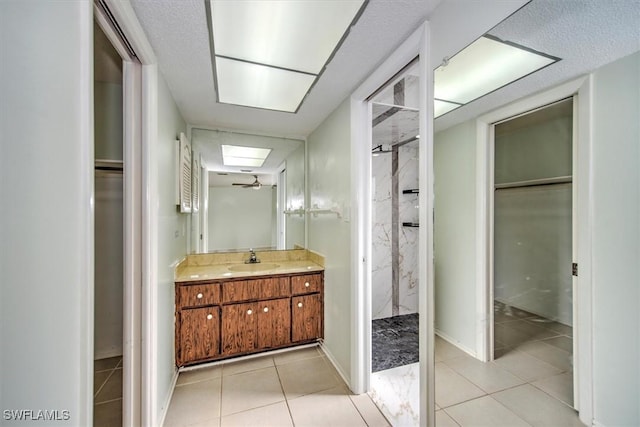 bathroom featuring a skylight, ceiling fan, tile patterned flooring, walk in shower, and vanity