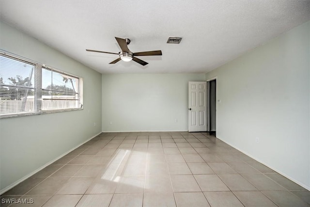 tiled empty room with ceiling fan and a textured ceiling