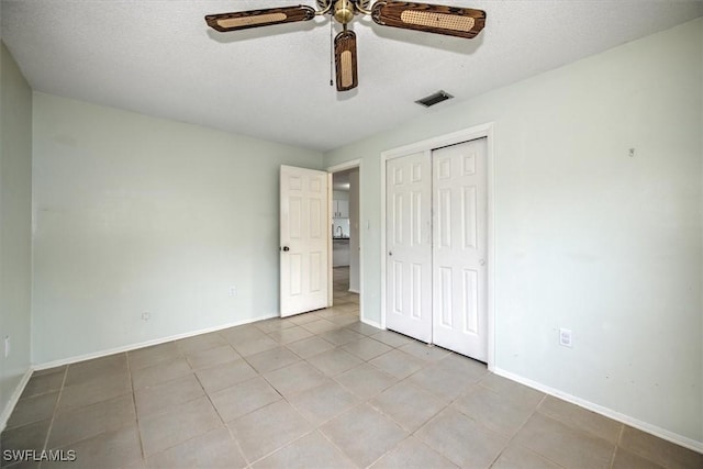 unfurnished bedroom with ceiling fan, light tile patterned floors, a closet, and a textured ceiling