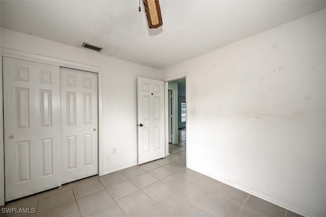 unfurnished bedroom with a closet, light tile patterned flooring, and ceiling fan