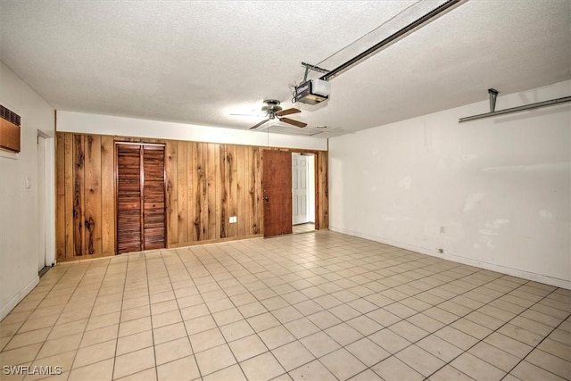 interior space with ceiling fan, wooden walls, and a textured ceiling