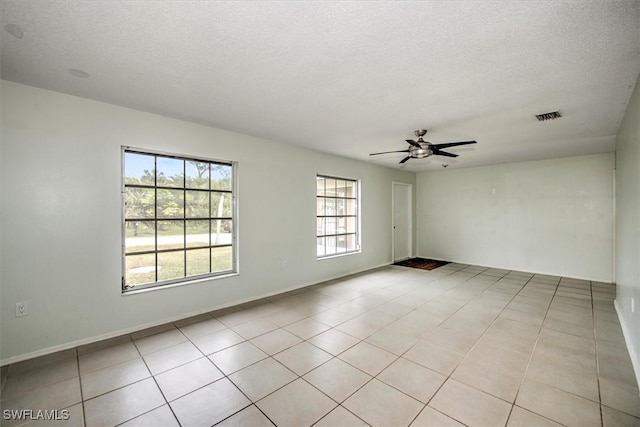 empty room featuring ceiling fan, a textured ceiling, and light tile patterned floors