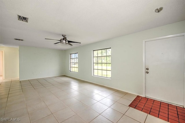 tiled empty room featuring ceiling fan and a textured ceiling