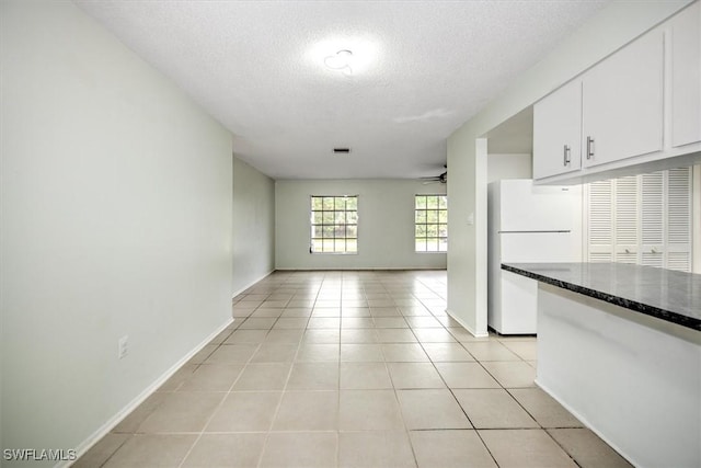 kitchen featuring ceiling fan, light tile patterned flooring, white cabinetry, a textured ceiling, and white refrigerator