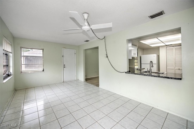 tiled empty room with ceiling fan and a textured ceiling