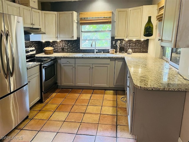 kitchen featuring appliances with stainless steel finishes, tasteful backsplash, sink, light tile patterned floors, and light stone counters