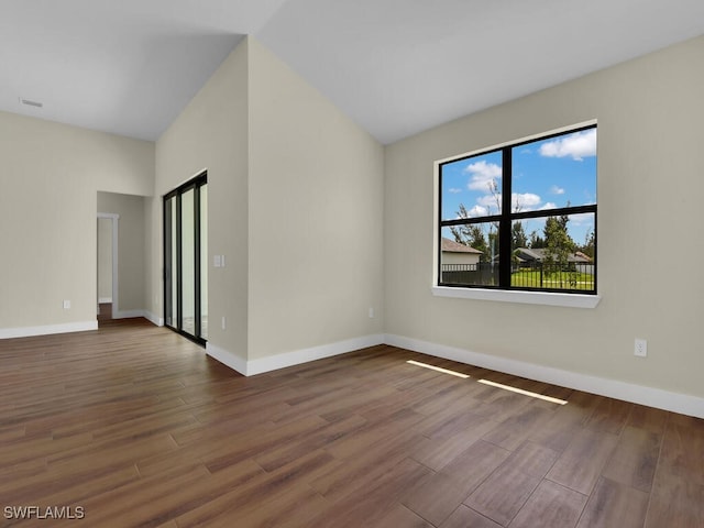 unfurnished room with baseboards, vaulted ceiling, and wood finished floors