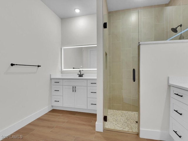 full bathroom with baseboards, a shower stall, vanity, and wood tiled floor