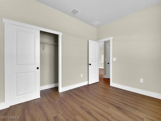 unfurnished bedroom featuring baseboards, a closet, visible vents, and dark wood-style flooring