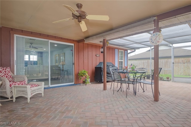 view of patio featuring a grill, ceiling fan, and glass enclosure