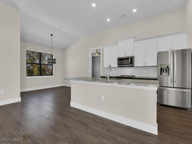kitchen with a center island with sink, white cabinets, appliances with stainless steel finishes, backsplash, and vaulted ceiling