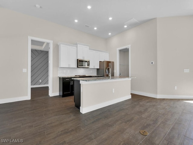 kitchen with a kitchen island with sink, backsplash, appliances with stainless steel finishes, baseboards, and white cabinets