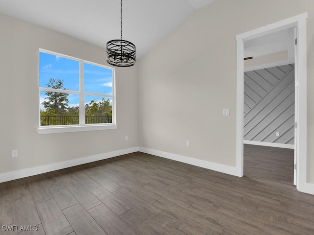 unfurnished dining area with baseboards, vaulted ceiling, wood finished floors, and a notable chandelier