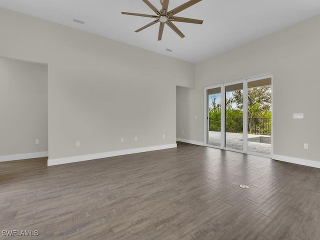 empty room featuring visible vents, baseboards, a high ceiling, dark wood-type flooring, and a ceiling fan