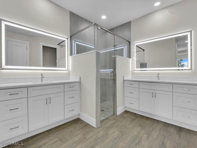 bathroom with a sink, wood finished floors, two vanities, and a shower stall