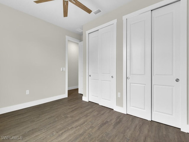 unfurnished bedroom with ceiling fan, two closets, baseboards, wood finished floors, and visible vents