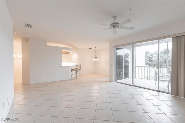 tiled empty room with ceiling fan with notable chandelier