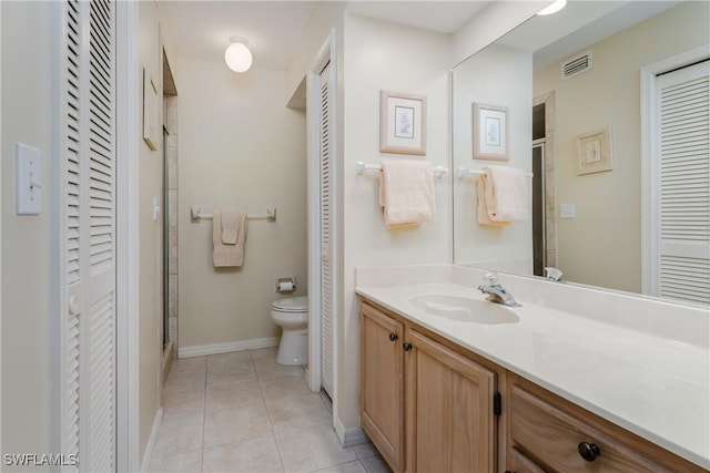 bathroom featuring tile patterned floors, toilet, a shower with door, and vanity