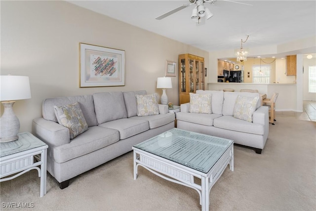 living room with light carpet and ceiling fan with notable chandelier