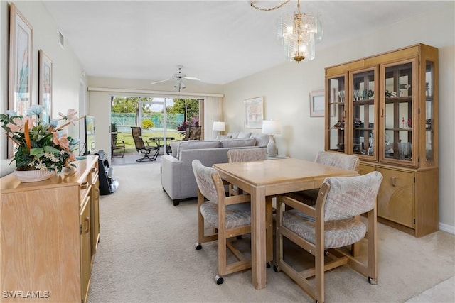 dining space with ceiling fan with notable chandelier and light carpet