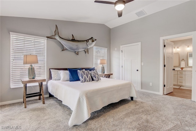 bedroom featuring ceiling fan, connected bathroom, light carpet, and lofted ceiling