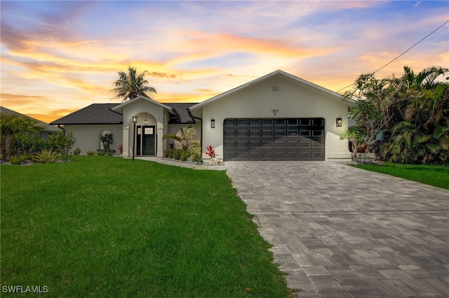 ranch-style house with a garage and a lawn