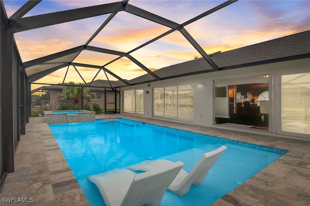 pool at dusk with an in ground hot tub, a lanai, and a patio