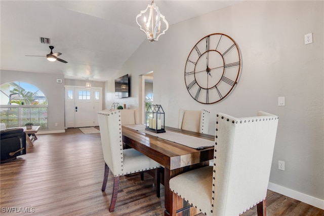 dining area featuring vaulted ceiling, dark wood-type flooring, and ceiling fan with notable chandelier