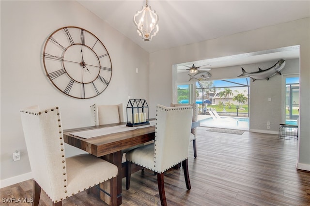 dining area featuring ceiling fan with notable chandelier, wood-type flooring, and vaulted ceiling