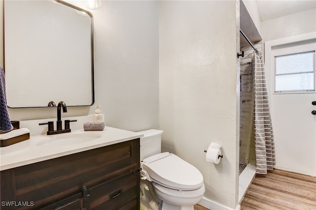 bathroom with wood-type flooring, toilet, vanity, and walk in shower