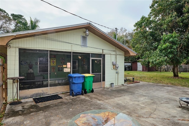 rear view of house featuring a patio area, a sunroom, and a lawn