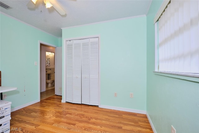 unfurnished bedroom with light hardwood / wood-style flooring, a closet, ceiling fan, and ornamental molding