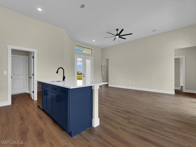 kitchen with sink, blue cabinets, french doors, ceiling fan, and a center island with sink