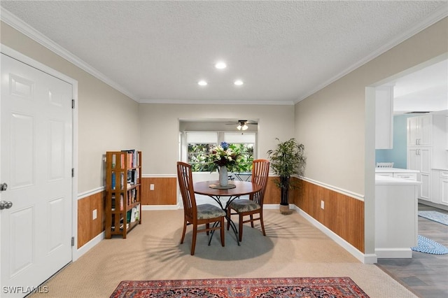 dining area featuring ceiling fan, a textured ceiling, ornamental molding, and wooden walls