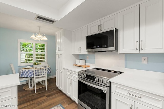 kitchen featuring pendant lighting, appliances with stainless steel finishes, white cabinetry, dark hardwood / wood-style floors, and a chandelier