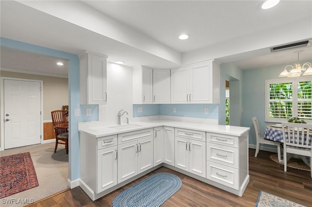 kitchen featuring dark wood-type flooring, kitchen peninsula, white cabinets, and sink