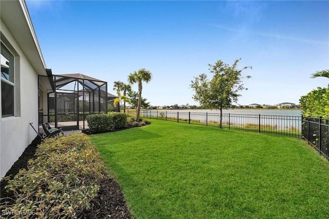 view of yard with glass enclosure, a water view, and a fenced backyard