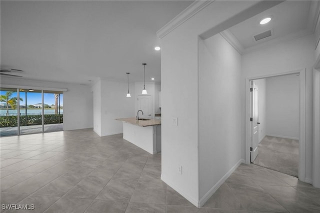 unfurnished living room with ornamental molding, visible vents, a sink, and baseboards