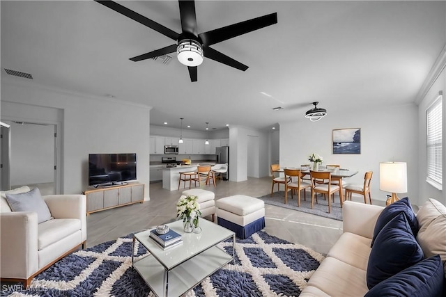 living room with ceiling fan, light tile patterned flooring, visible vents, and crown molding