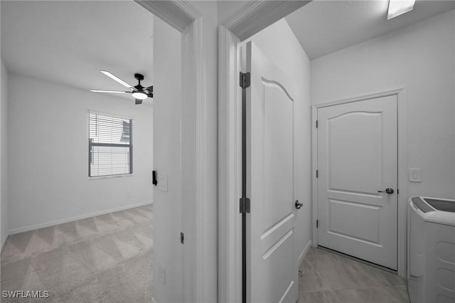 hallway featuring light carpet, washer / dryer, and baseboards