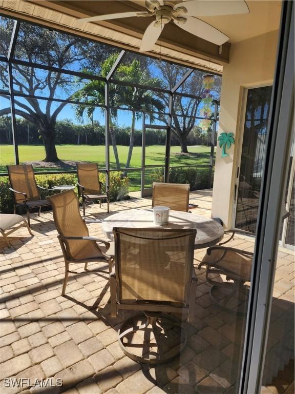 view of patio / terrace featuring ceiling fan and glass enclosure