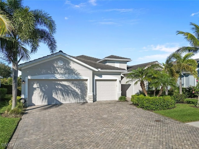 view of front of property with an attached garage, decorative driveway, and stucco siding