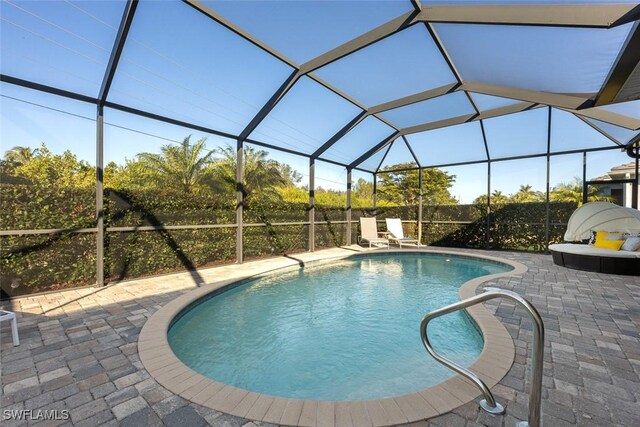 view of swimming pool featuring glass enclosure and a patio