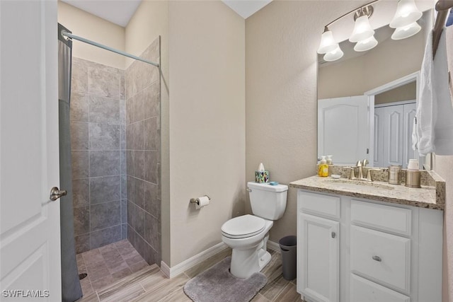 bathroom featuring toilet, a tile shower, and vanity