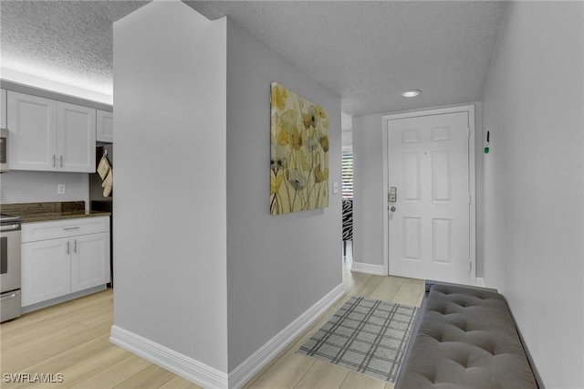 hallway featuring light hardwood / wood-style floors and a textured ceiling