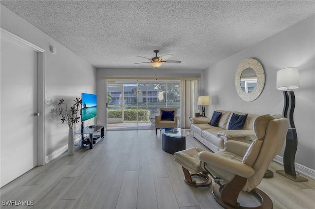 living room with ceiling fan, a textured ceiling, and light hardwood / wood-style flooring