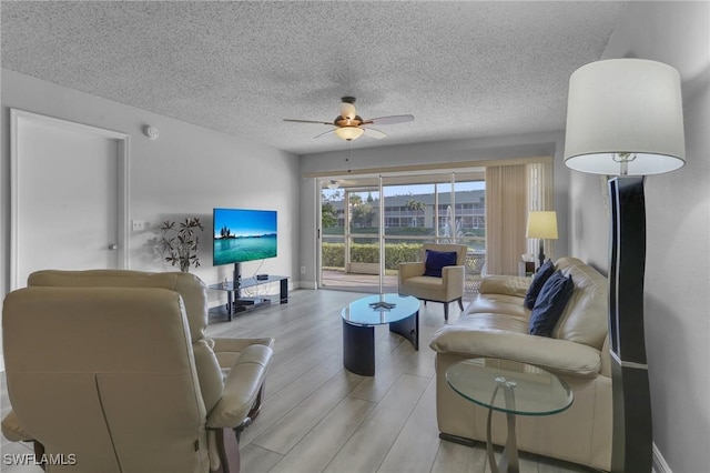 living room featuring a textured ceiling, ceiling fan, and light hardwood / wood-style flooring