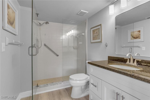 bathroom featuring toilet, a shower with door, and vanity