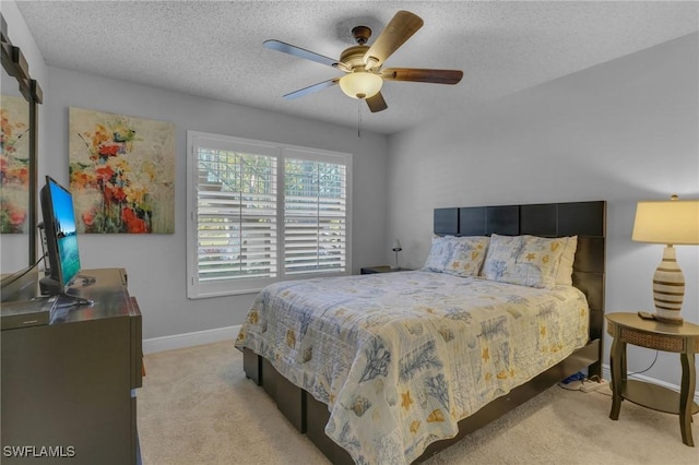 bedroom featuring a textured ceiling, ceiling fan, and light colored carpet