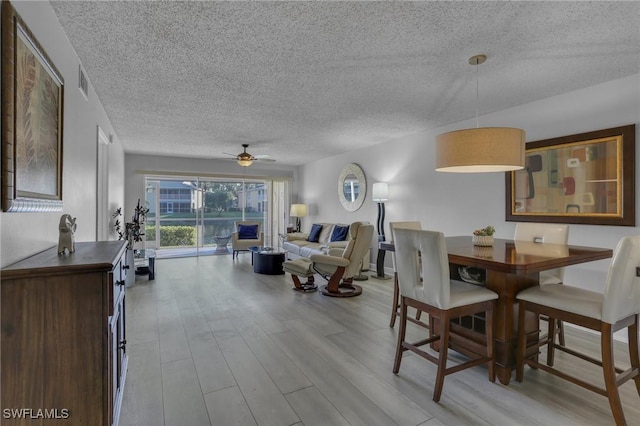 dining room featuring ceiling fan, a textured ceiling, and light hardwood / wood-style flooring